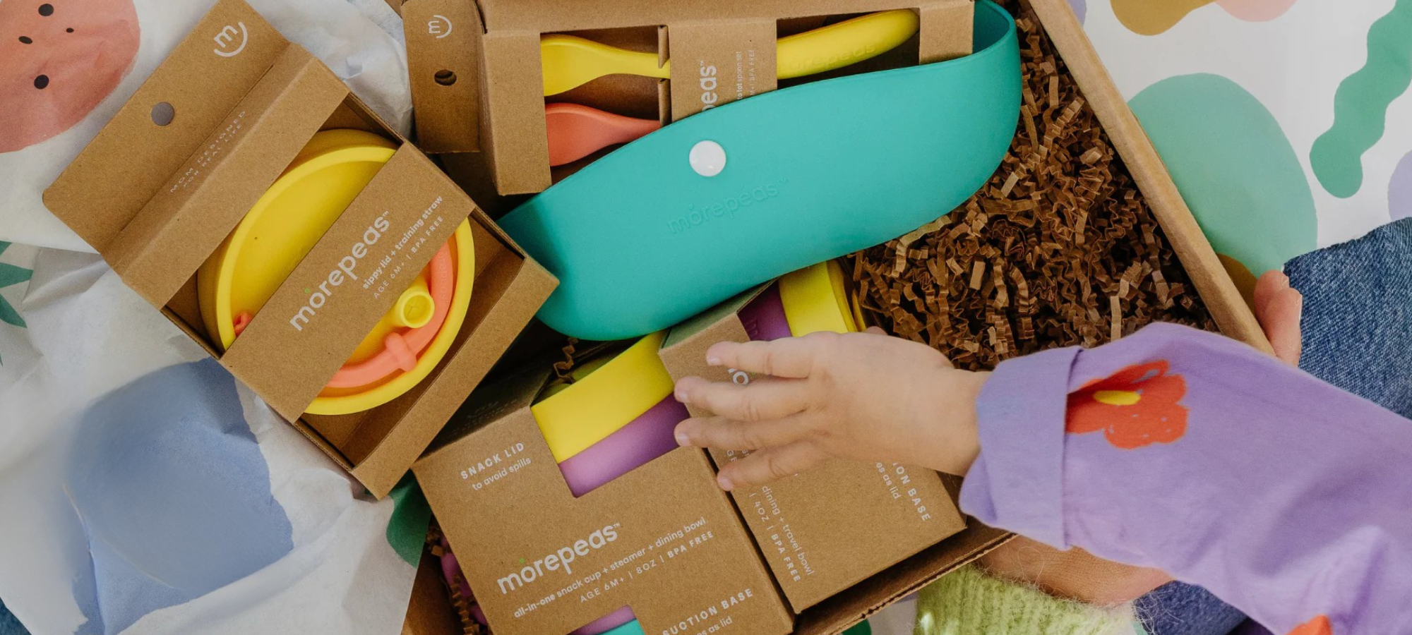 Overhead shot of child's hand opening a morepeas gift bundle