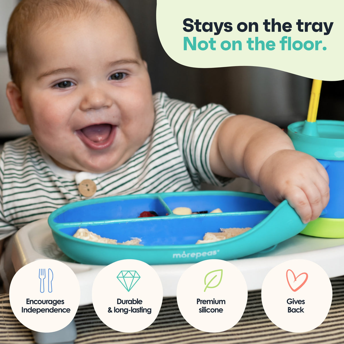 Smiling baby pulling on a Morepeas suction plate that stays on the high chair tray